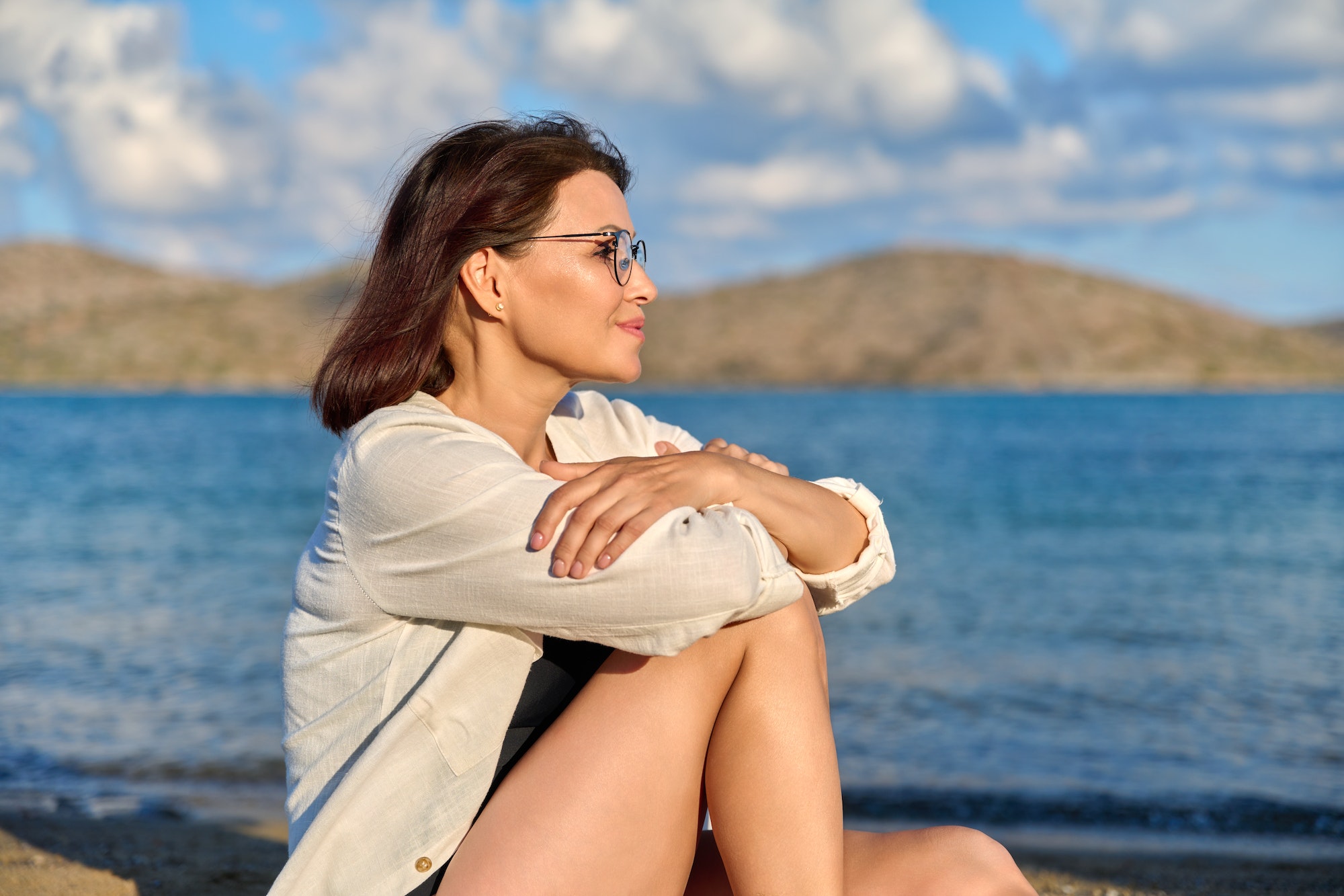 Beautiful 40s age woman looking away, profile view, sea scenic landscape